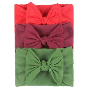 Detailed view of 3-pack nylon bow headbands in red, burgundy, and green for infants