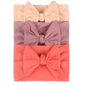 Detailed texture of three elastic nylon baby headbands with handmade bows in soft pastel colors