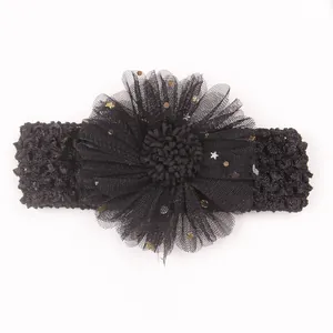 Détail de bandeau bébé avec fleur en maille noire ornée de paillettes dorées et argent