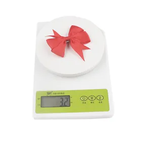 Detail showing red grosgrain ribbon bow hair clip weighing 3.2g on electronic scale