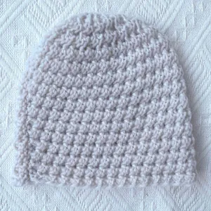 Off-white hand-knitted warm crochet baby winter hat with thick textured weave