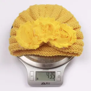 Detail shot showing the lightweight 43.5g yellow knit baby hat with floral accents