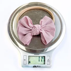 Close-up showing a pink nylon baby bow headband on a scale weighing 11.7 grams