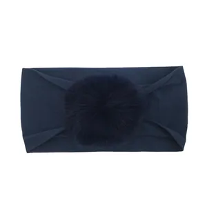 Dettaglio della fascia per neonati blu navy con un grande pompon in ecopelliccia soffice