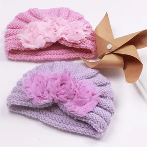 Detailed view of pink and purple baby knit hats with layered 3D fabric flower accents