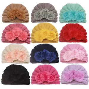 Detail showing twelve colors of baby knitted turban hats with floral decorations