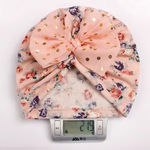 Close-up showing the 21.9g lightweight pink floral baby turban hat with a large bow on a scale