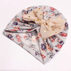 Close-up of floral baby turban hat with large mesh bow and gold foil polka dots