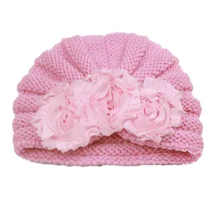 Detailed texture of pink knit baby turban hat with three decorative lace flowers
