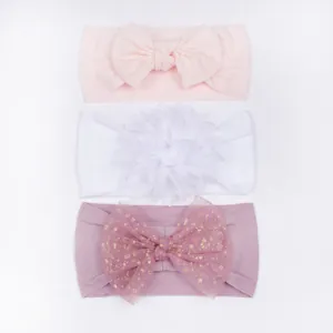 Vue détaillée de trois bandeaux souples pour bébé avec nœuds roses et fleurs blanches