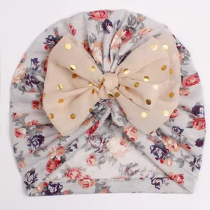 Detailed texture of baby floral turban hat with a large golden polka dot mesh bow