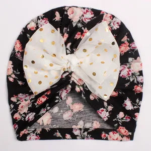 Close-up of baby floral turban with white gold polka dot bow and rose patterns