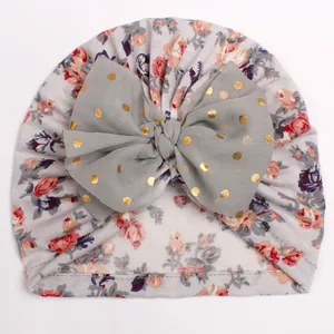 Detail of baby floral turban hat with light grey rose print and large mesh gold dot bow
