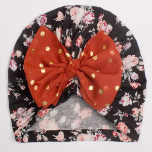 Detail of baby floral knot hat with large orange polka dot bow and soft cotton fabric