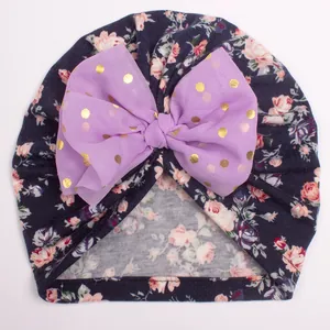 Detail of floral baby turban with purple chiffon bow and gold polka dot pattern