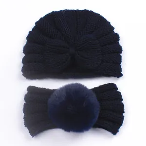 Detailed knit texture of navy blue baby turban hat and headband with faux fur pom pom