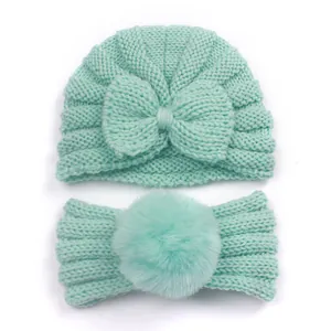 Detail of mint green baby knit set featuring bow beanie and pompom headband
