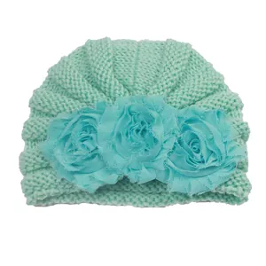 Detailed knit texture and layered flower ornaments on a mint green baby winter hat