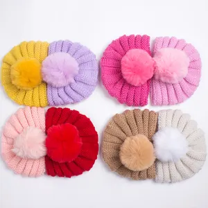 Détail de bonnets tricotés pour bébés avec de grands pompons en fausse fourrure douce