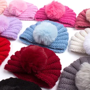 Détail de bonnets en maille côtelée pour bébé aux couleurs variées avec pompons