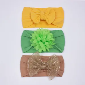 Détail de trois bandeaux pour bébés avec nœuds jaunes et fleurs en tissu vert tendre