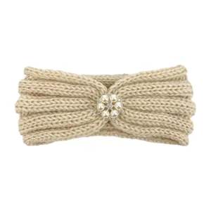 Detail of beige knitted baby headband with decorative pearl and rhinestone flower
