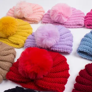 Vue à plat de bonnets en tricot pour bébé aux couleurs variées avec pompons en fourrure