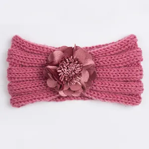 Detalle del tejido de una diadema de punto para bebé rosa oscuro con una flor de seda