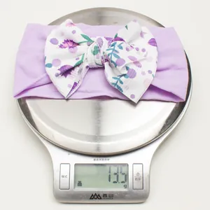 Detail shot showing a lightweight purple baby floral bow headband weighing 13.5g on a scale