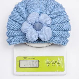 Berretto neonato azzurro in maglia con grande fiore e peso visualizzato 46,5g