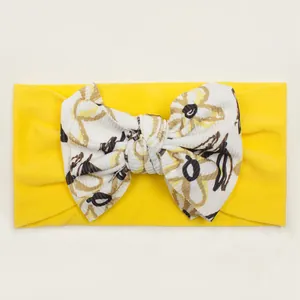 Detail of yellow ribbed baby headband featuring a bohemian floral pattern bow tie