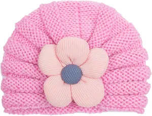 Dettaglio cappello neonato in maglia rosa con fiore in velluto a coste fatto a mano