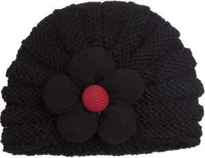 Dettaglio cappello neonato in maglia nera con fiore 3D e bottone rosso al centro