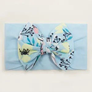 Detail of baby elastic headband with a blue floral bow in soft ribbed knit fabric