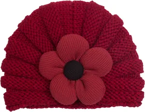 Dettaglio del cappello a turbante in maglia rossa per neonato con grande fiore 3D