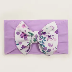 Close-up of baby headband with purple floral bow and textured ribbed fabric pattern