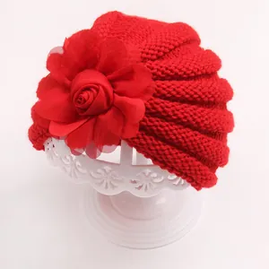 Détail d'un bonnet en tricot rouge pour bébé avec une grande fleur en mesh 3D