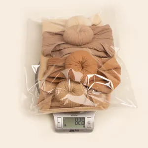 Set of 4 elastic knit baby donut headbands in earth tones on a scale weighing 82.6g