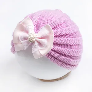 Detail of baby knit turban hat featuring pink bow with lace and pearl accents