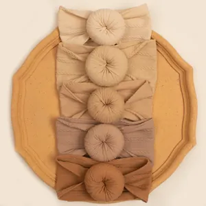 Close-up of five neutral-toned ribbed baby headbands with donut knot details