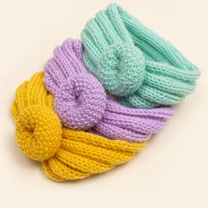 Détail de trois bandeaux tricotés pour bébé avec nœuds donuts en vert menthe mauve et jaune
