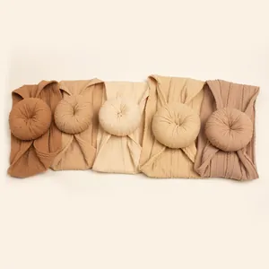Flat lay of five earth-toned jacquard donut baby headbands in a gradient color set