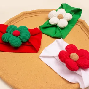 Detailed view of three soft elastic Christmas headbands with corduroy flowers in a tray