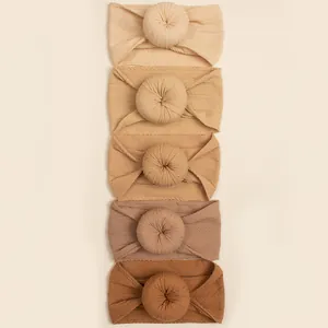 Detail showing five assorted earth-tone baby donut headbands in soft ribbed knit fabric
