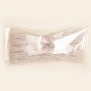 Bandeau bébé en maille beige avec nœud torsadé dans son emballage transparent