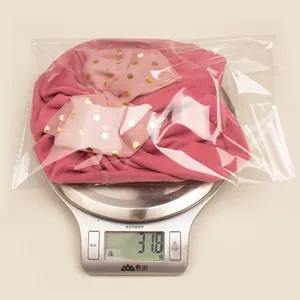 Pink infant bow hat weighing 31.8g on a digital scale for material thickness verification