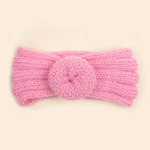 Détail d'un bandeau bébé en maille rose avec texture côtelée et fleur au crochet
