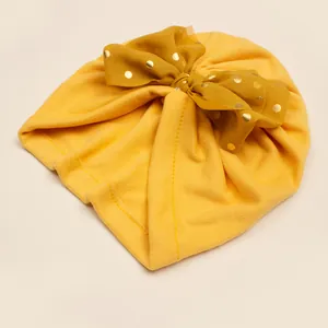 Detail of yellow baby turban hat with gold polka dot chiffon bow and soft knit fabric