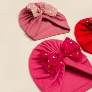 Cozy winter baby turban hats with large gold dot mesh bows in pink and red