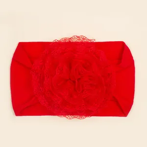 Detailopname van een rode babyhoofdband van nylon met een grote handgemaakte kanten bloem